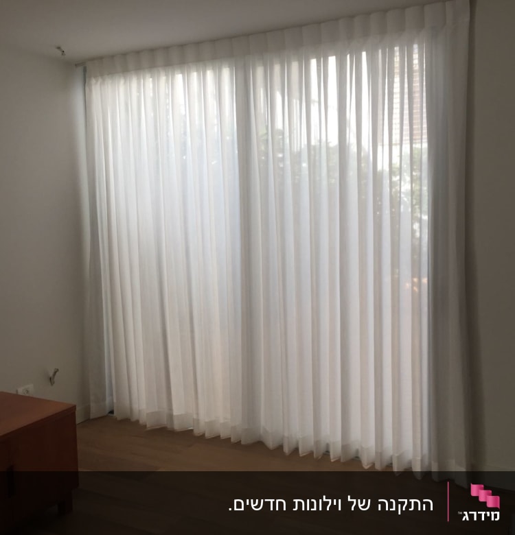 וילון לבן שקוף תלוי על חלון גדול